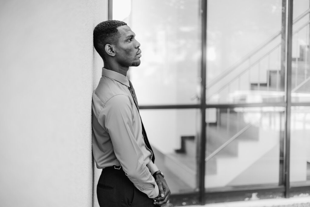 Daniel Osei Afrifa in shirt and tie, leaning against a wall (black-and-white portrait)